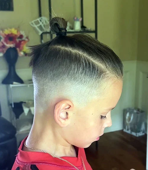 35 Popular Boy’s Haircuts Trending in 2025 (Cool & Stylish Ideas for All Ages) 17 This image has an empty alt attribute; its file name is Top-Knot-with-Mid-Fade.webp